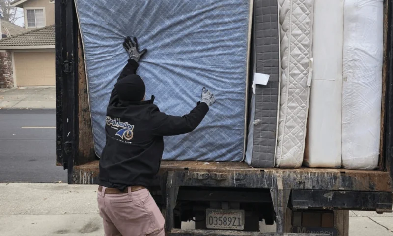 Bay Hauling professional loading multiple used mattresses onto a truck for responsible disposal and recycling